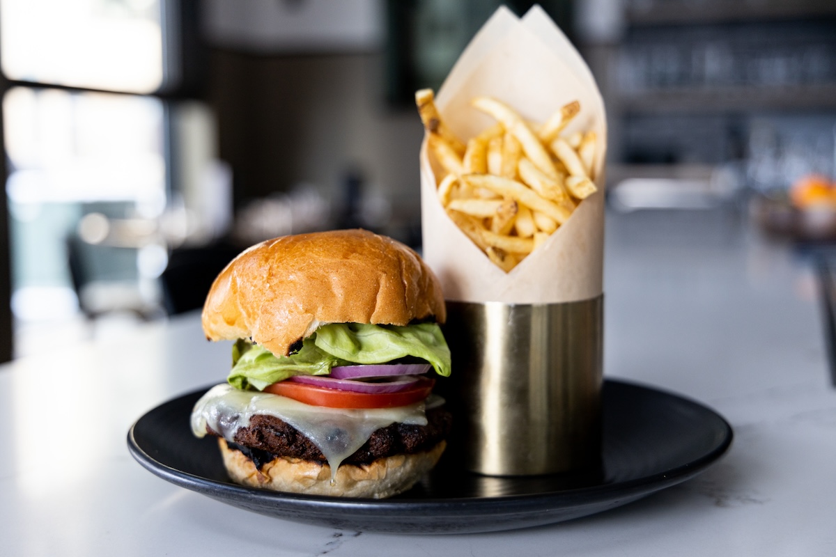 black plate with cheeseburger and fries on it