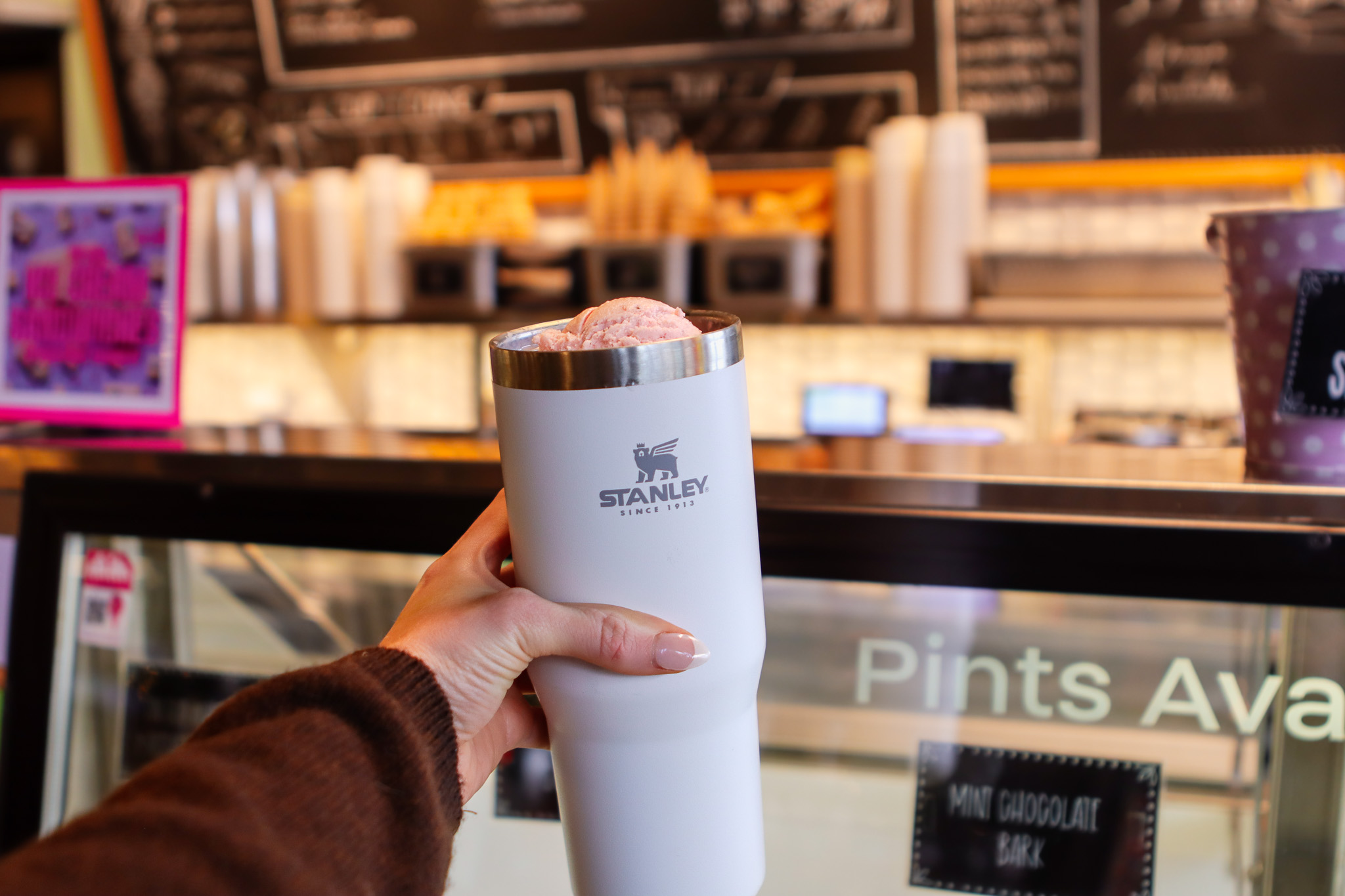 hand holding stanley cup in front of ice cream case