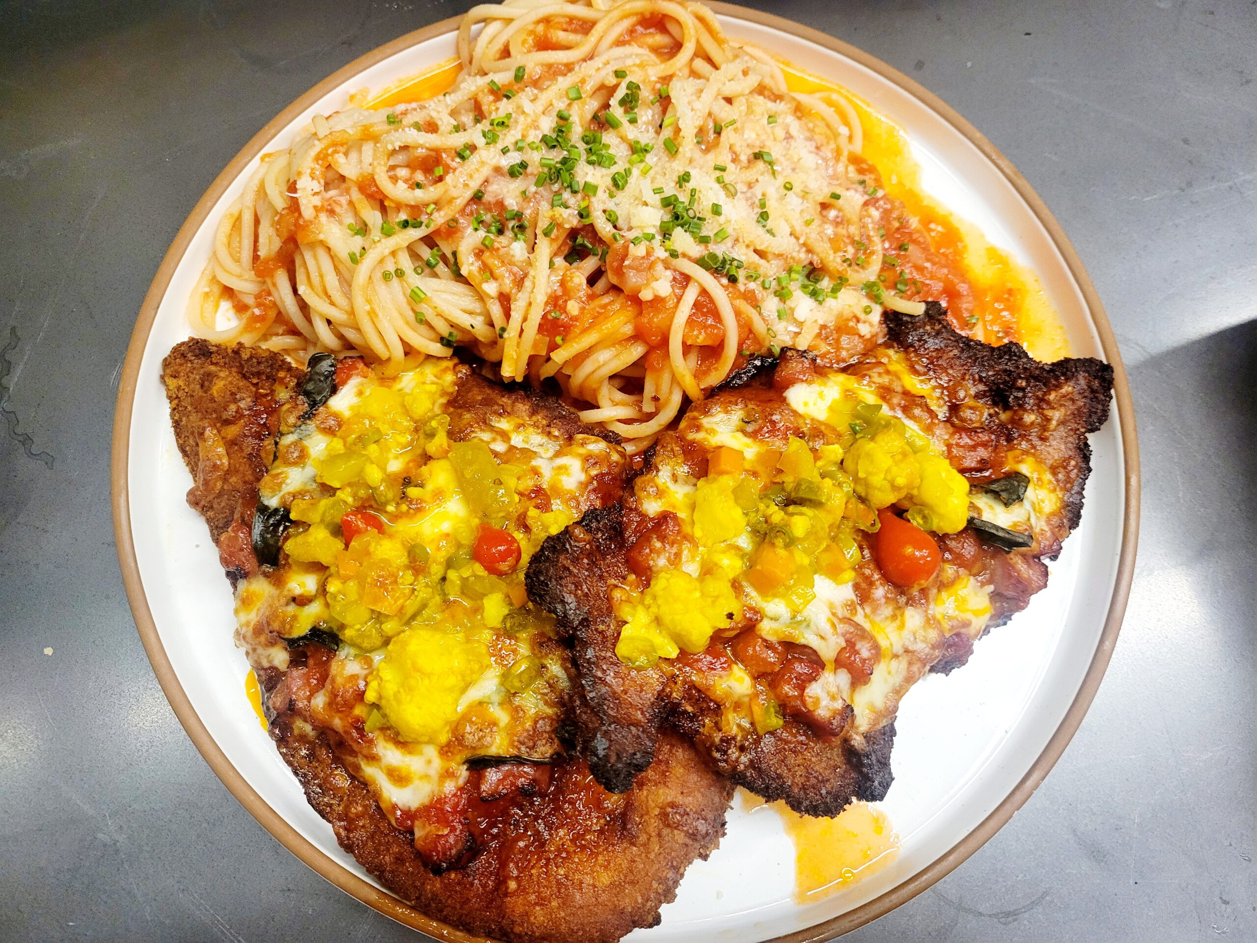 chicken parm on a white plate with noodles