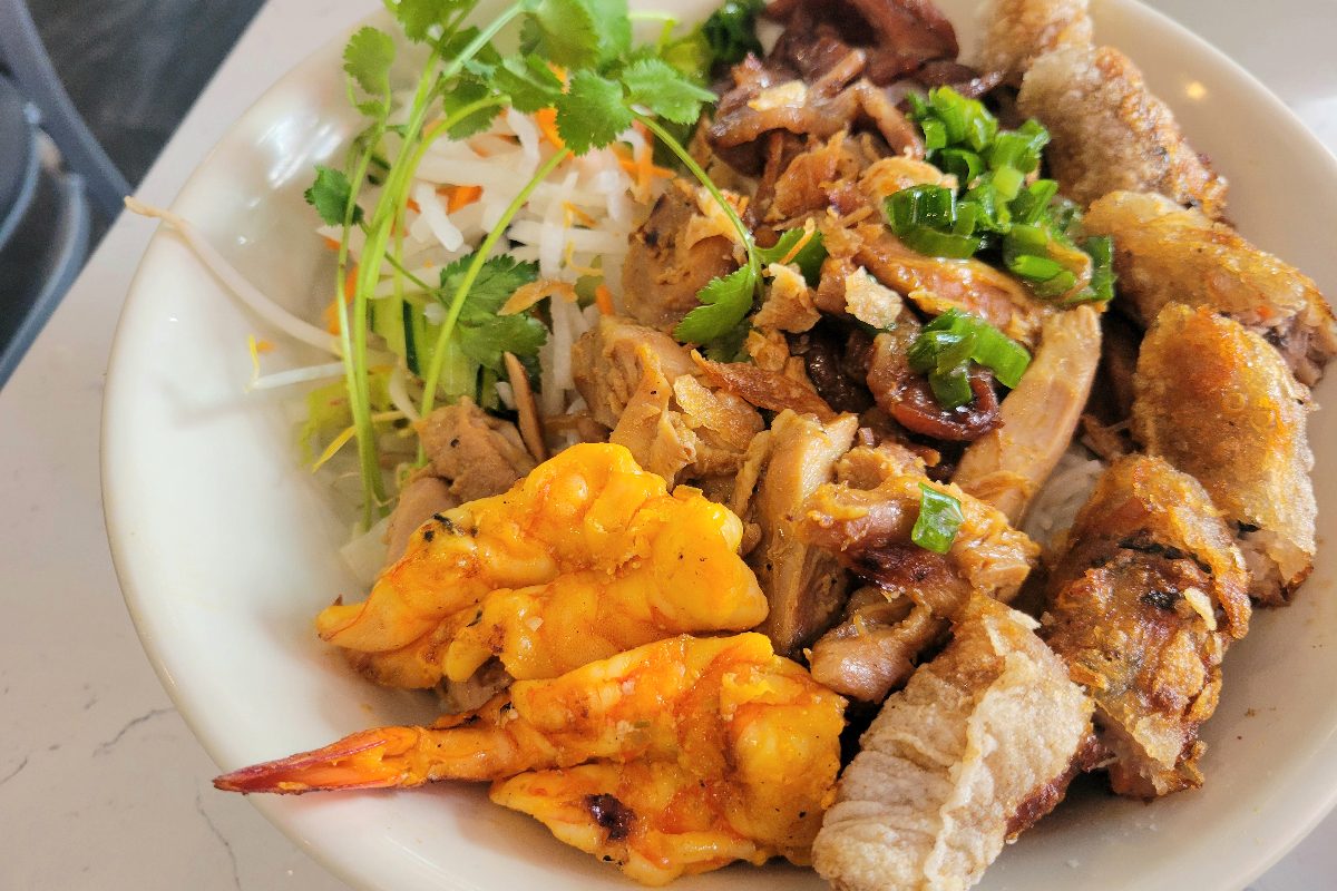 white bowl of shrimp, herbs, chicken, spring roll and noodle